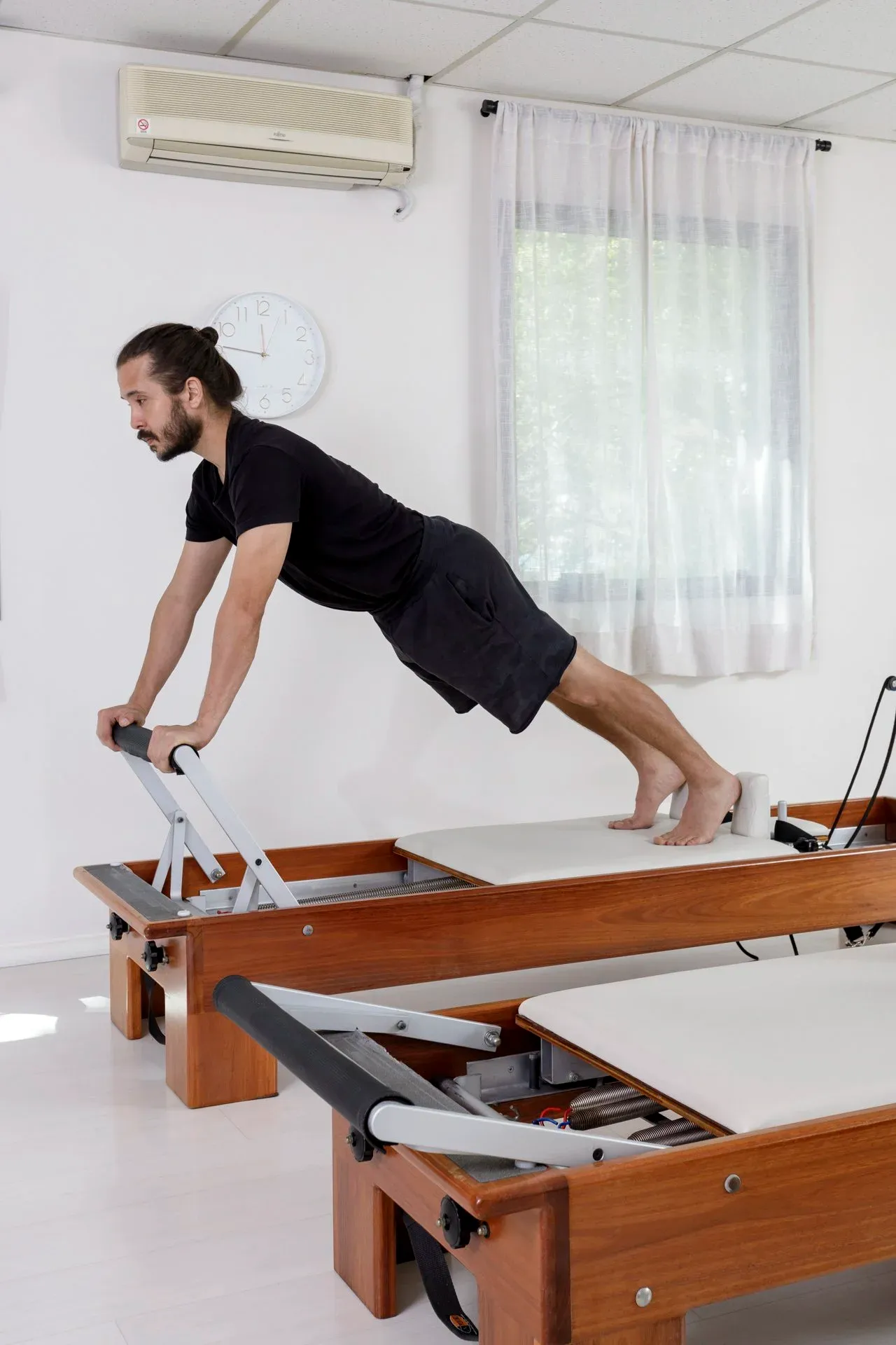 Aluno em posição de prancha no reformer de madeira