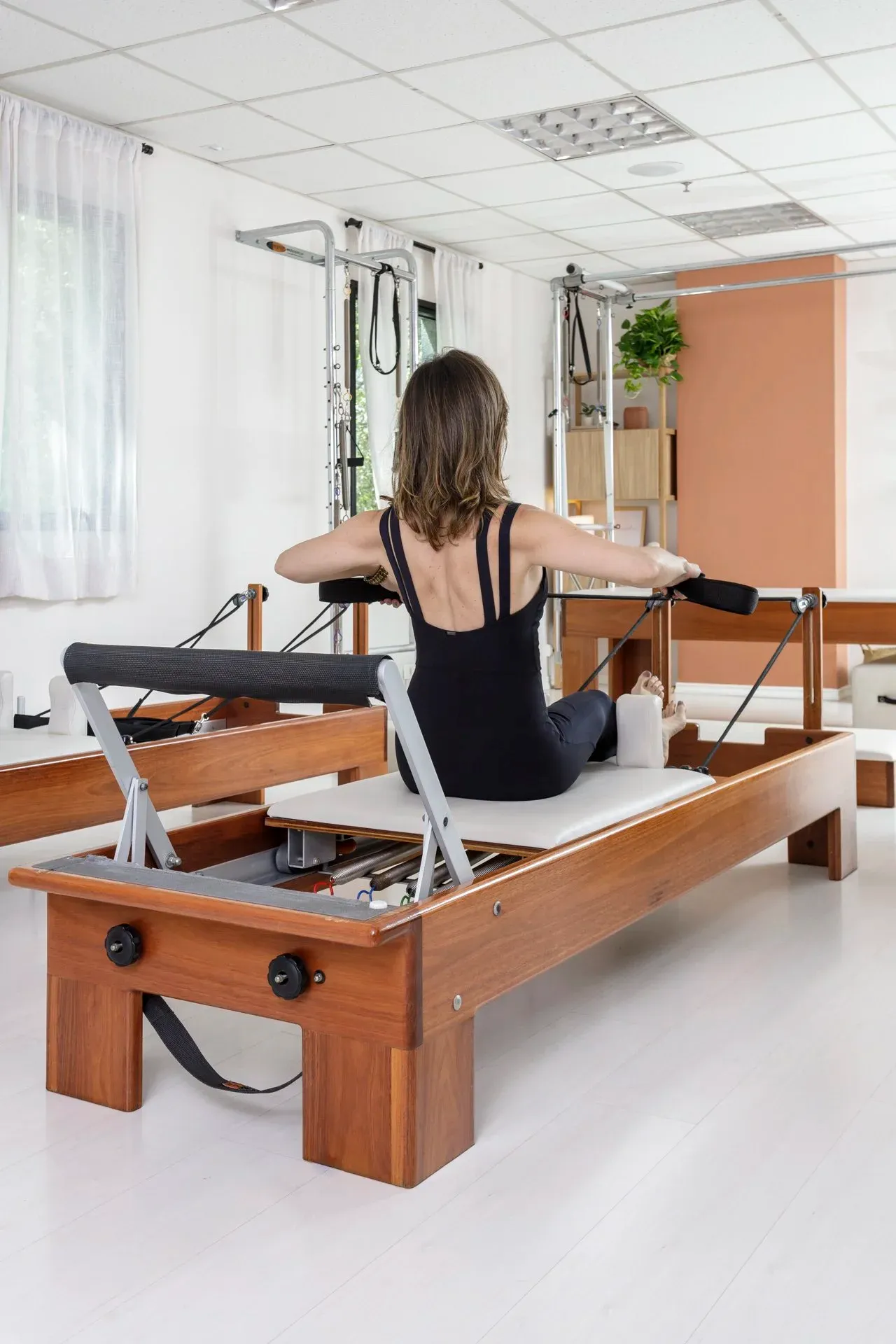 Aluna realizando exercício de remada sentada no reformer