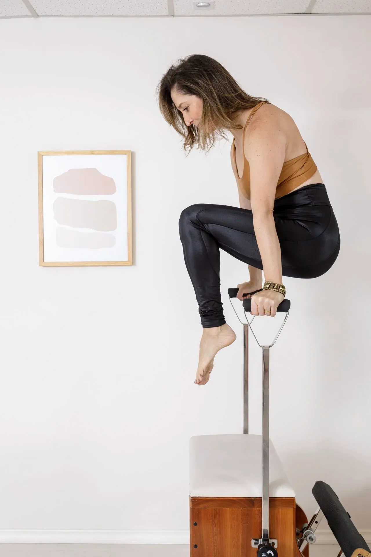Aluna em posição de equilíbrio suspenso na cadeira de pilates