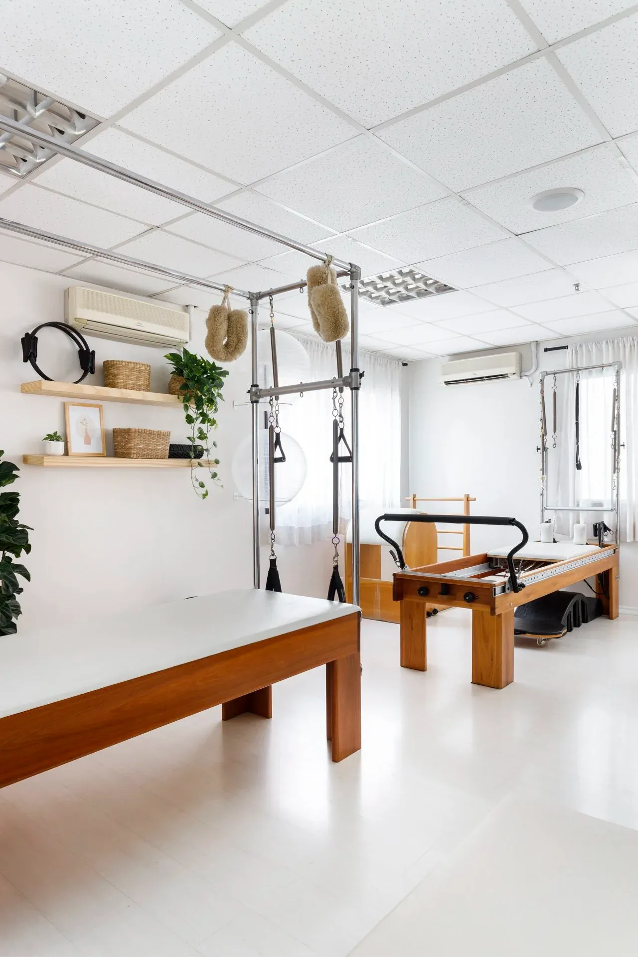 Sala com reformers e cadillac de madeira, prateleiras com acessórios